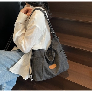 Deep grey canvas tote bag with brown leather patch shown on model in a lifestyle setting