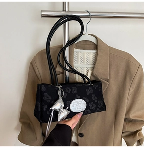 Dettaglio borsa a spalla in jacquard nero con ciondolo a farfalla argento e logo