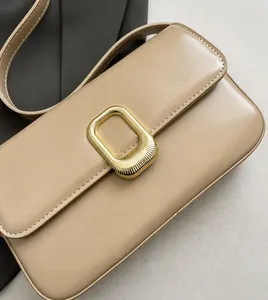 Detalle de bolso de hombro beige con cuero sintético texturizado y hebilla metálica dorada