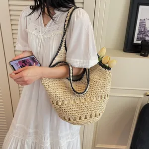 Detail of straw tote bag with black contrast trim and hollow woven patterns