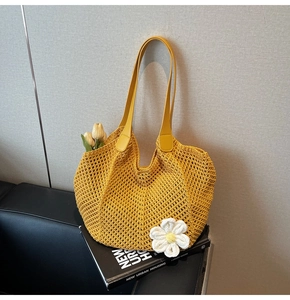 Close-up of a yellow woven tote bag featuring a 3D white flower and smooth PU handles