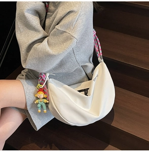Detalle de bolso media luna blanco con correa de cuerda trenzada y colgante de muñeca suave
