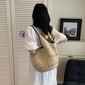 Detailed view of spacious woven straw tote bag with black trim and inner flower decoration
