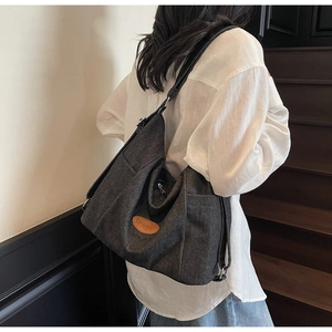 Detail of dark grey canvas tote bag showing the side pocket and leather logo patch