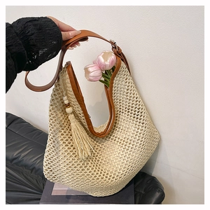 Detail der gewebten Stroh-Hobo-Tasche mit braunem Lederbesatz und modischer Quaste