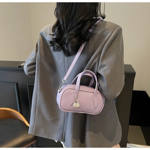 Detail view of purple pebbled leather handbag with metal lock charm on a grey suit model