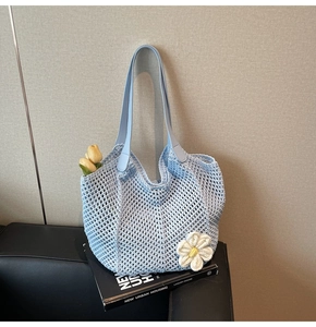 Close-up of light blue crochet tote bag featuring handcrafted daisy flowers and leather straps