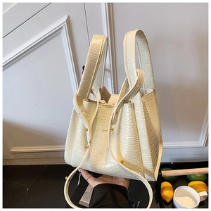Detail of cream white bucket bag with crocodile pattern and gold logo lettering
