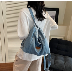 Detailed view of light blue denim hobo bag with adjustable strap and leather logo patch