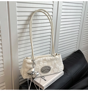 Dettaglio della borsa sottobraccio in nylon crema con ricami floreali 3D e ciondolo