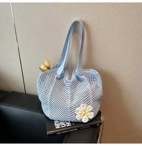 Detail of light blue crochet tote bag featuring 3D white flower and PU leather handles