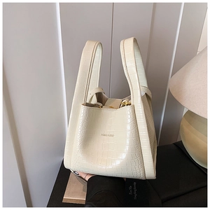 Detail of crocodile pattern texture and metal buckle on cream white bucket bag