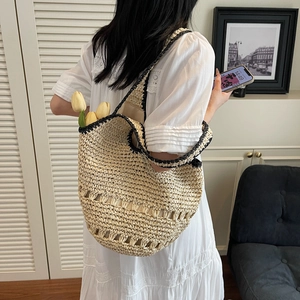 Close-up of woven straw tote bag featuring black contrast trim and hollow pattern details