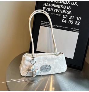 Dettaglio del tessuto jacquard bianco con texture floreale e ciondolo a fiocco argento