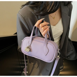 Close-up of purple litchi grain leather bag with silver lock and handle held by model