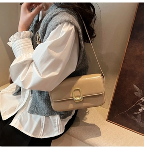 Detalle del bolso de hombro en cuero pulido beige con elegante hebilla metálica dorada