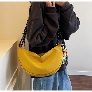 Detalle de bolso medialuna de lona amarilla con correa de hombro de cuerda trenzada