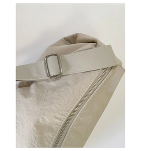 Detailed macro view of the beige nylon fabric texture and silver metal buckle on the bag
