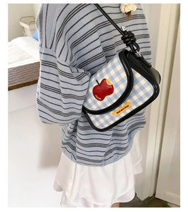 Detail of blue gingham saddle bag with red apple patch and Not anxious text label