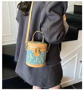 Detail der Denim-Beuteltasche mit blauem Herzmuster und braunem Lederbesatz am Model