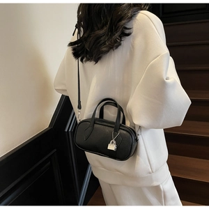 Detailed texture of black lychee grain leather handbag with silver metallic charm