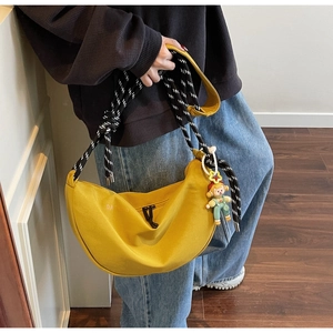 Detalle de bolso medialuna amarillo con correa de cuerda trenzada y colgante de payaso
