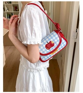 Detail of blue plaid canvas bag with red apple patch and Not Anxious label