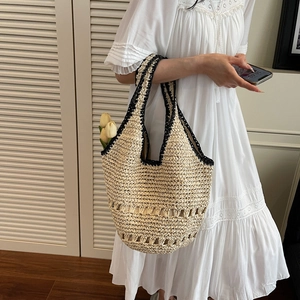 Detail of hand-woven straw tote bag with black crochet trim and intricate hollow pattern