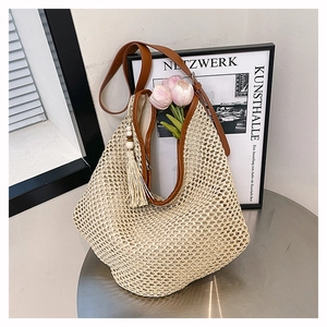 Detailaufnahme einer gewebten Strohtasche mit braunen Ledergriffen und beiger Quaste