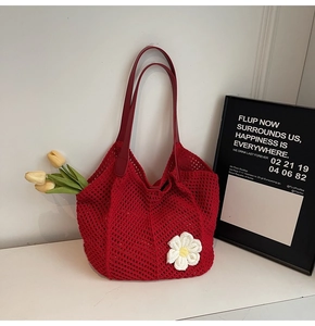 Close-up of red woven tote bag with a 3D knit flower and durable leather handles