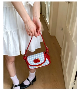 Detail of red gingham plaid handbag with apple embroidery and stylish knotted handle