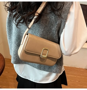 Detalle de bolso bandolera beige con hebilla dorada en una modelo con estilo