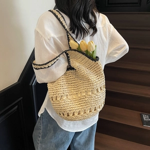 Detail of hand-woven straw tote with black contrast trim and hollow pattern