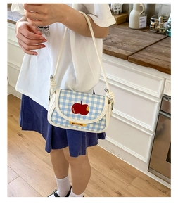 Detailed close-up of blue gingham crossbody bag featuring a red apple embroidery