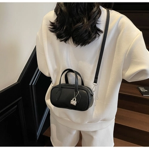Detail of black pebbled leather crossbody pillow bag with silver charm on model