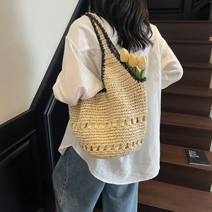 Detail of woven straw tote bag with black piping and hollow-out design for spring vacation
