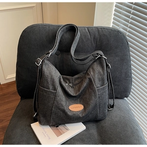 Detail of gray canvas tote bag with brown leather patch on a textured velvet chair