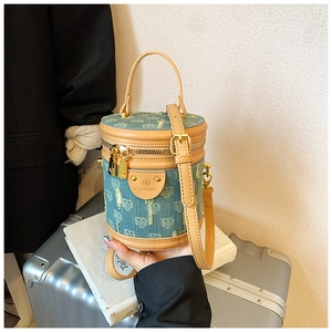 Detail der blauen Denim Beuteltasche mit Herz-Jacquard und Lederbesatz auf silbernem Koffer