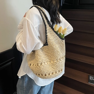 Detail of hand-woven beige tote with black trim and hollow decorative patterns