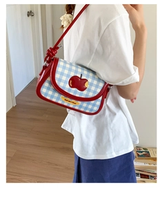 Detail of blue plaid shoulder bag with red apple embroidery and knotted strap