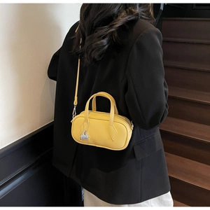 Detail of a bright yellow pebble leather mini pillow bag with silver lock ornament