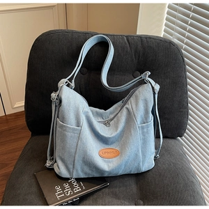 Close-up of light blue denim tote bag texture with leather logo and silver metal buckles