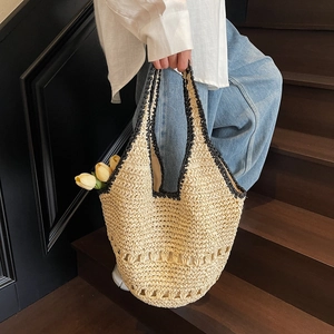 Close-up of straw tote bag featuring black woven trim and delicate hollow-out pattern