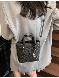 Borsa a tracolla intrecciata nera con ciondolo a cuore su modella in blazer grigio
