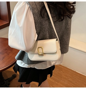 Detalle del bolso bandolera minimalista en cuero crema con hebilla dorada grabada