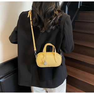 Detailed macro of yellow litchi grain leather bag with a silver padlock on black blazer