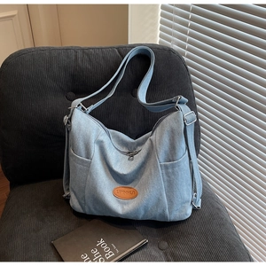 Detail of light blue denim canvas tote bag with brown leather patch on a chair