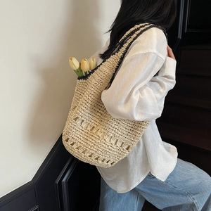 Detail of hand-woven straw tote bag with black trim accents and hollow patterned weave