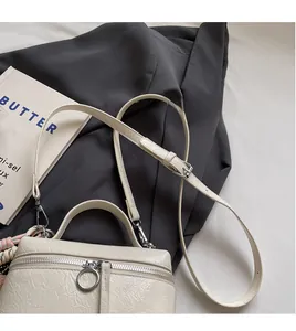 Close-up of cream pleated leather bucket bag with smooth zipper and adjustable strap