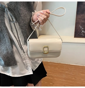 Detalle del bolso rectangular crema con hebilla de metal dorado y cuero sintético liso